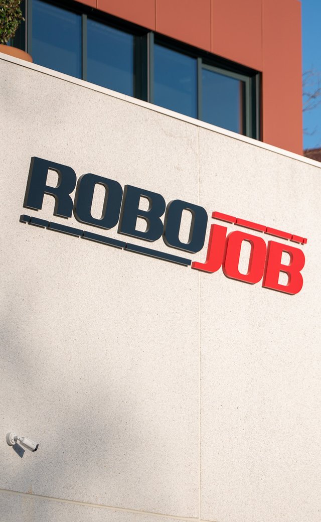 robojob headquarters with the big logo on the facade and a few trees